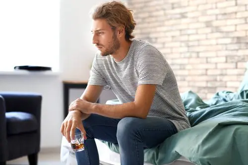 man with whiskey glass sitting and looking depressed