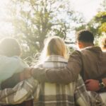 A group of friends stand outdoors with their arms around each other, symbolizing unity, support, and community in recovery.