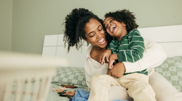 Ivory Plains - Use Laughter to Support Better Health. A woman and a child sit on a couch laughing with one another.